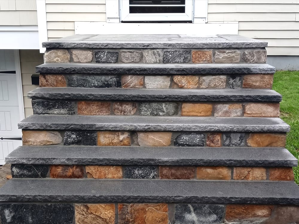Stone faced entry steps with cut treads beside a house