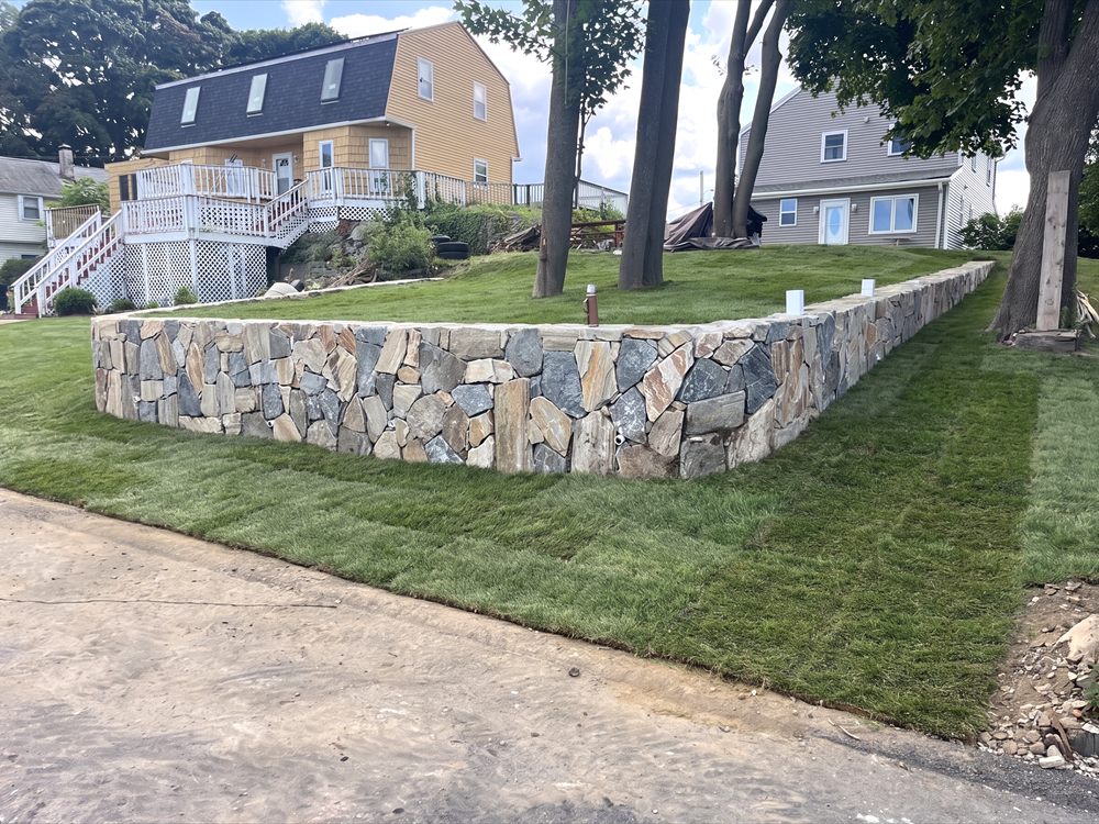 Long stone retaining wall with fresh sod laid along a residential front yard